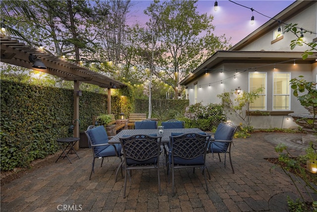 patio terrace at dusk with outdoor dining area, a fenced backyard, and a pergola