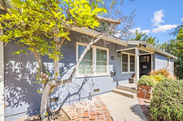 entrance to property featuring crawl space and stucco siding