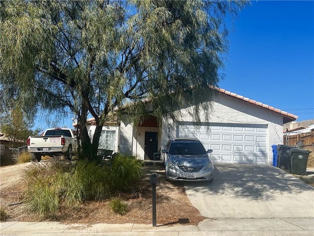 single story home with a tiled roof, an attached garage, driveway, and stucco siding