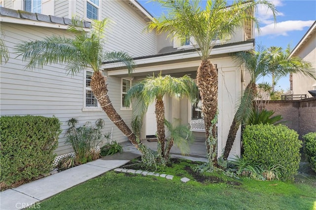 entrance to property featuring a yard and fence