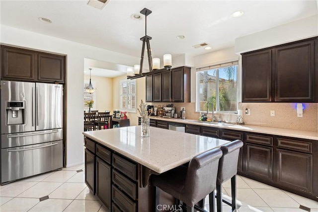 kitchen featuring a sink, dark brown cabinetry, appliances with stainless steel finishes, pendant lighting, and backsplash