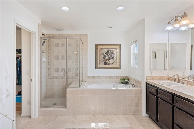 full bathroom with visible vents, a walk in closet, a garden tub, a stall shower, and vanity