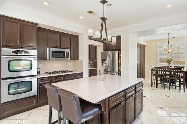 kitchen featuring dark brown cabinets, light tile patterned flooring, visible vents, and appliances with stainless steel finishes