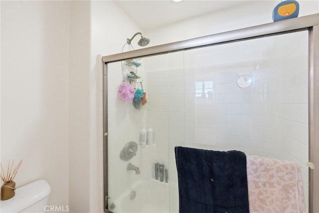 bathroom featuring enclosed tub / shower combo and toilet