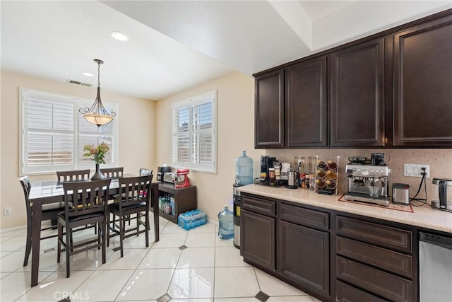 kitchen featuring visible vents, dark brown cabinets, pendant lighting, light countertops, and decorative backsplash