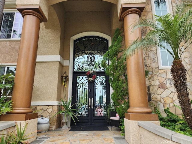 doorway to property with stone siding and stucco siding