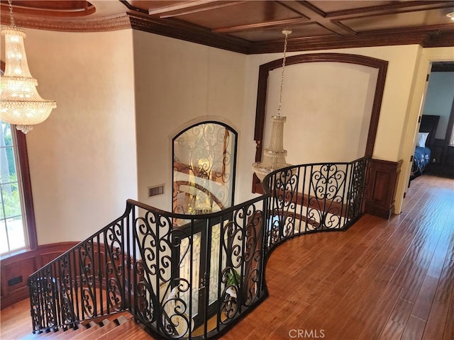 stairway featuring a wainscoted wall, visible vents, wood finished floors, crown molding, and a chandelier