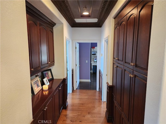 corridor featuring light wood-style flooring, baseboards, and ornamental molding