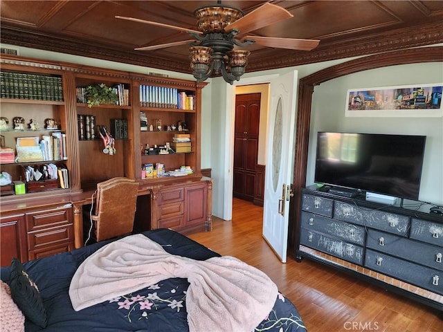 bedroom featuring wood finished floors, ornamental molding, and built in study area