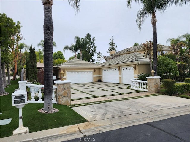 view of front of property with stucco siding, driveway, a front yard, an attached garage, and a tiled roof