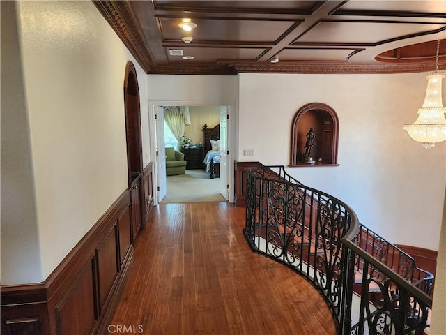 hall featuring ornamental molding, an upstairs landing, wood finished floors, arched walkways, and coffered ceiling