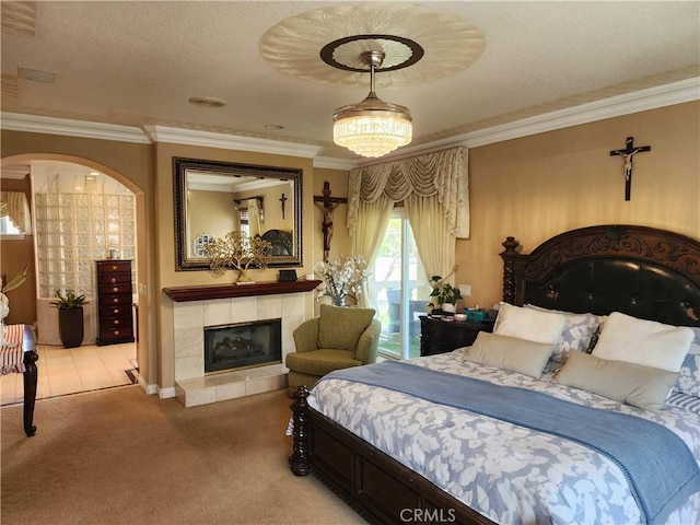 bedroom with a tiled fireplace, light colored carpet, a textured ceiling, and ornamental molding