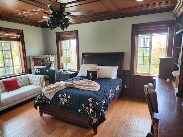 bedroom with coffered ceiling, ceiling fan, hardwood / wood-style flooring, wainscoting, and crown molding