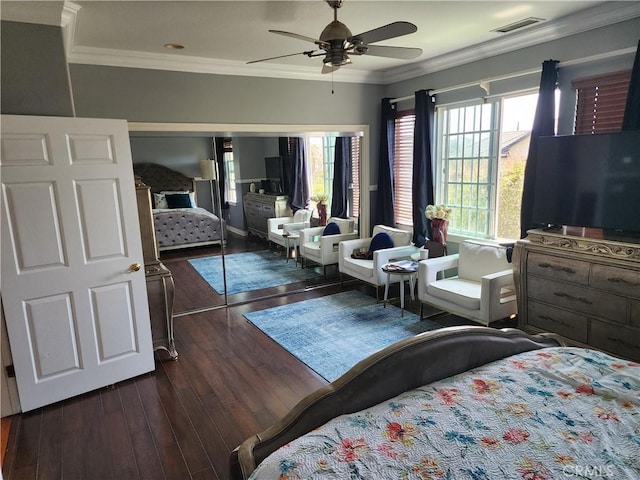 bedroom with dark wood finished floors, visible vents, a ceiling fan, and ornamental molding