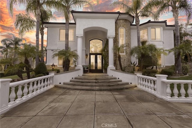 doorway to property featuring french doors, stone siding, and stucco siding