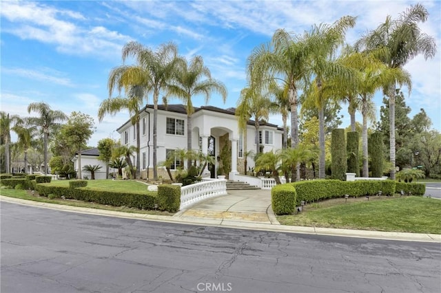 mediterranean / spanish home featuring a fenced front yard, stucco siding, driveway, and a front lawn