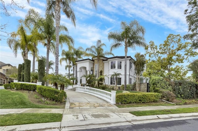 mediterranean / spanish-style home featuring a fenced front yard, driveway, and stucco siding