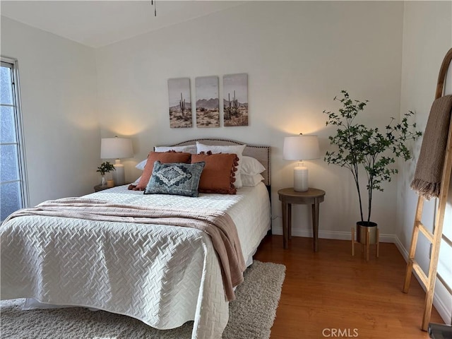 bedroom with baseboards and wood finished floors