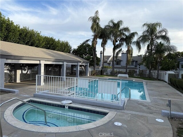 community pool featuring a patio, a community hot tub, and fence