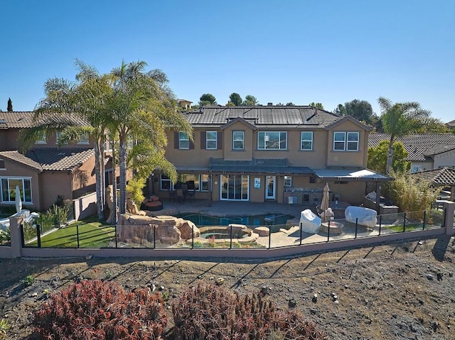 view of front of property with a patio area, a fenced backyard, a pool with connected hot tub, and stucco siding