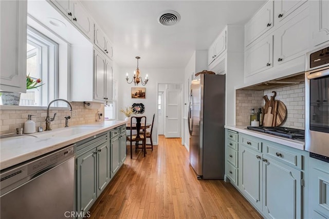 kitchen featuring visible vents, light wood-style flooring, a sink, light countertops, and appliances with stainless steel finishes