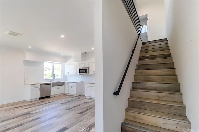 staircase featuring recessed lighting, visible vents, and wood finished floors