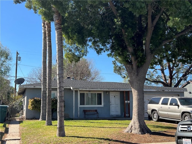 ranch-style home with a front lawn, a gate, an attached garage, and stucco siding