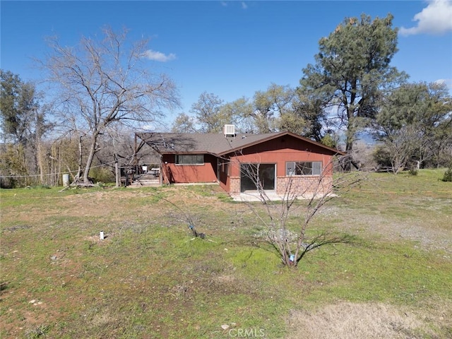 back of property featuring a yard and brick siding