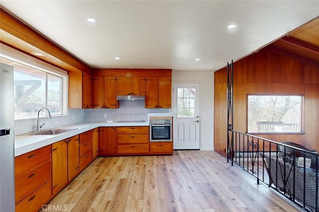 kitchen with brown cabinetry, light countertops, extractor fan, and stainless steel oven