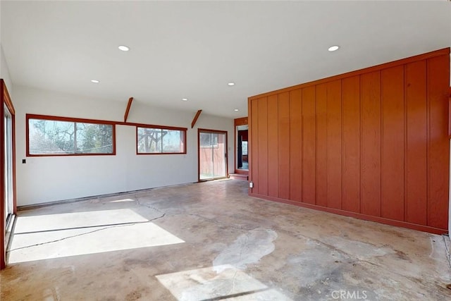 spare room featuring recessed lighting, concrete flooring, and wood walls