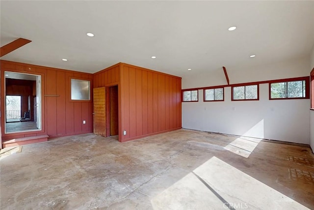 spare room featuring wooden walls, recessed lighting, and concrete floors