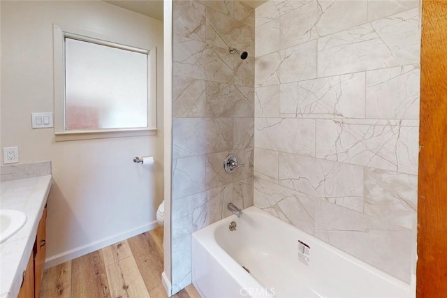 full bathroom featuring toilet, wood finished floors, washtub / shower combination, baseboards, and vanity