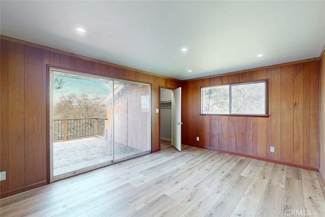 spare room with recessed lighting, wood walls, light wood-type flooring, and baseboards