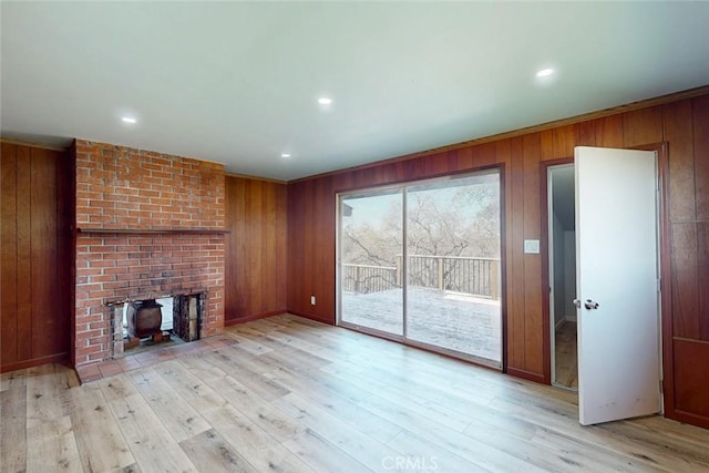 unfurnished living room featuring recessed lighting, light wood-style floors, and wood walls