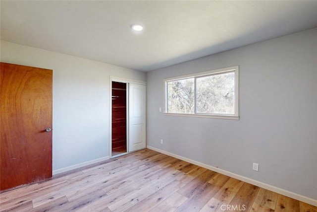 unfurnished bedroom featuring a closet, baseboards, and wood finished floors