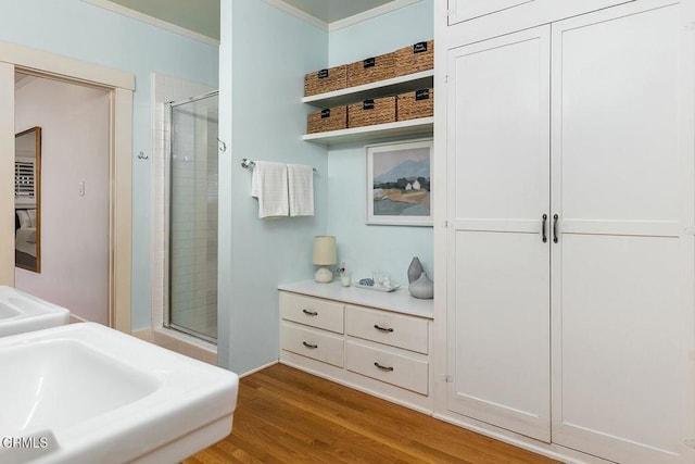 full bathroom featuring crown molding, wood finished floors, and a stall shower