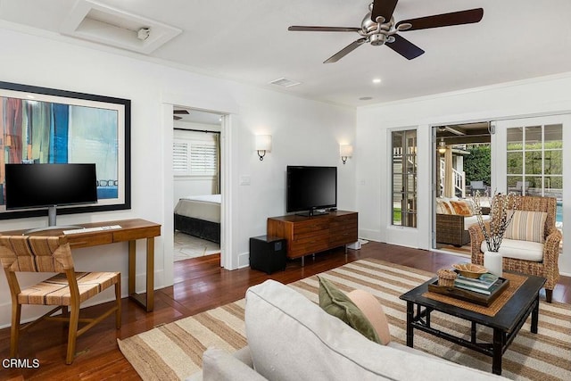 living area with visible vents, wood finished floors, baseboards, and ceiling fan