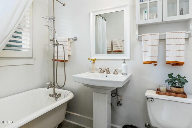 full bath featuring toilet, a freestanding bath, and a shower with curtain