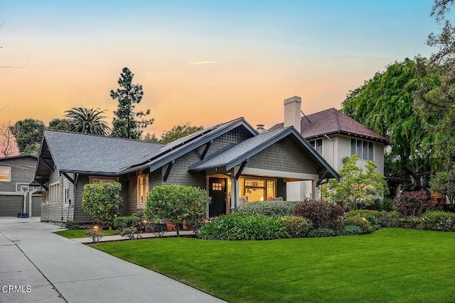 view of front of home featuring a garage, a chimney, a front lawn, and roof with shingles