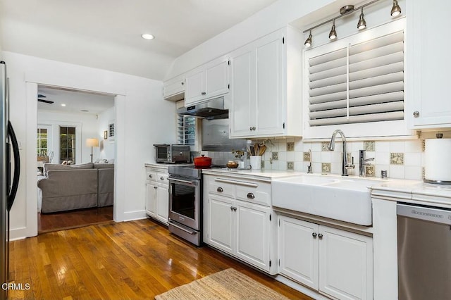 kitchen featuring under cabinet range hood, light countertops, appliances with stainless steel finishes, white cabinetry, and a sink