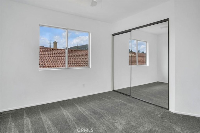 unfurnished bedroom featuring baseboards, a closet, carpet floors, and ceiling fan