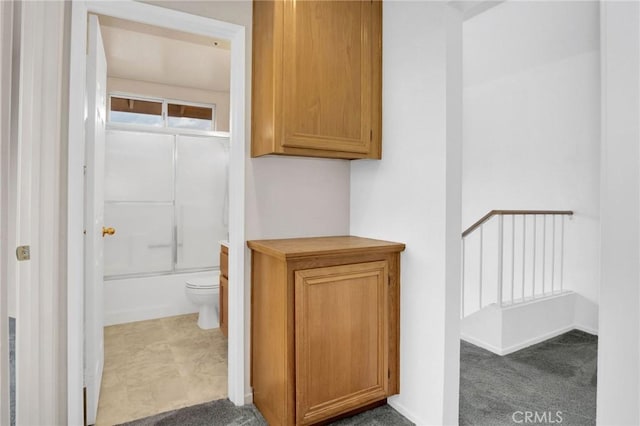 bathroom featuring toilet, baseboards, and enclosed tub / shower combo