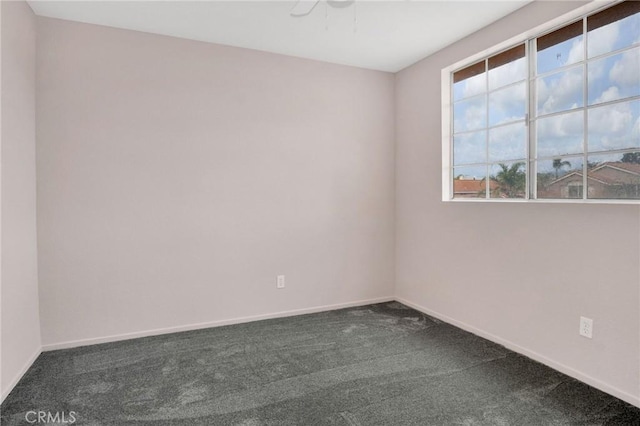 unfurnished room with dark colored carpet and baseboards