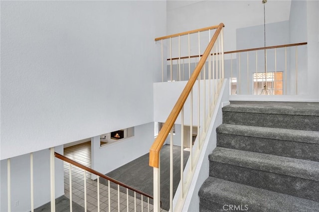 staircase with a towering ceiling and carpet flooring