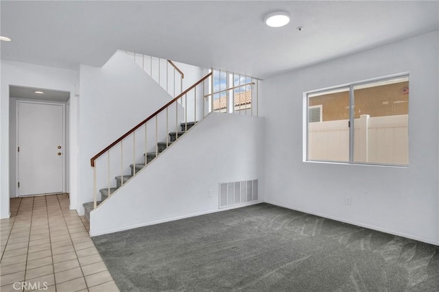 interior space featuring visible vents, carpet, tile patterned flooring, and stairway