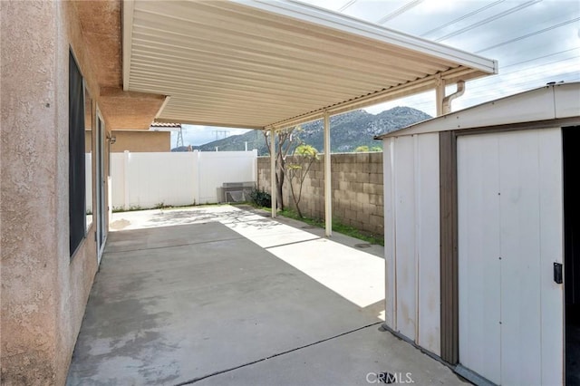 view of patio with a storage unit, an outdoor structure, a fenced backyard, and a mountain view