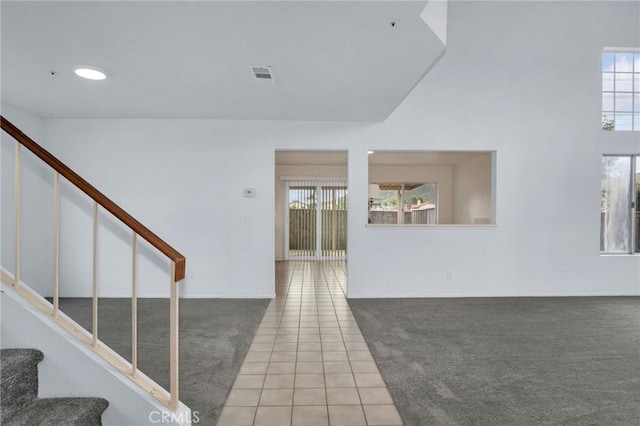 staircase featuring tile patterned flooring, visible vents, carpet flooring, and a healthy amount of sunlight