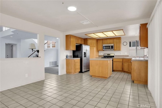 kitchen with visible vents, light tile patterned flooring, stainless steel appliances, light countertops, and a center island