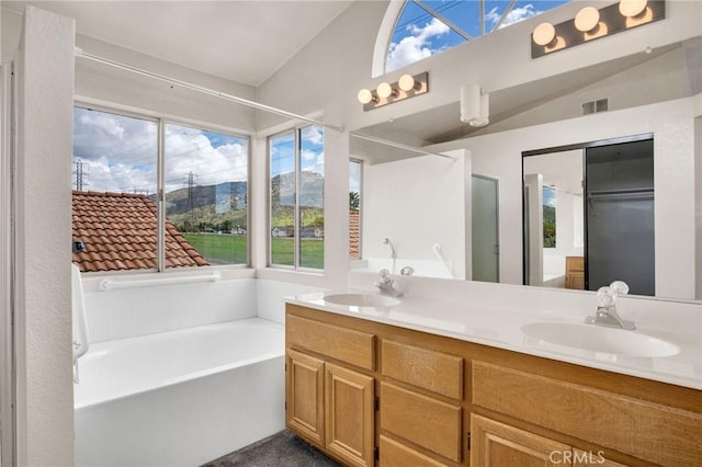 bathroom with a bath, visible vents, double vanity, and a sink