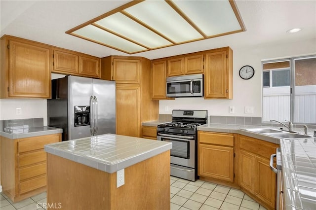 kitchen with a sink, tile countertops, light tile patterned floors, and stainless steel appliances